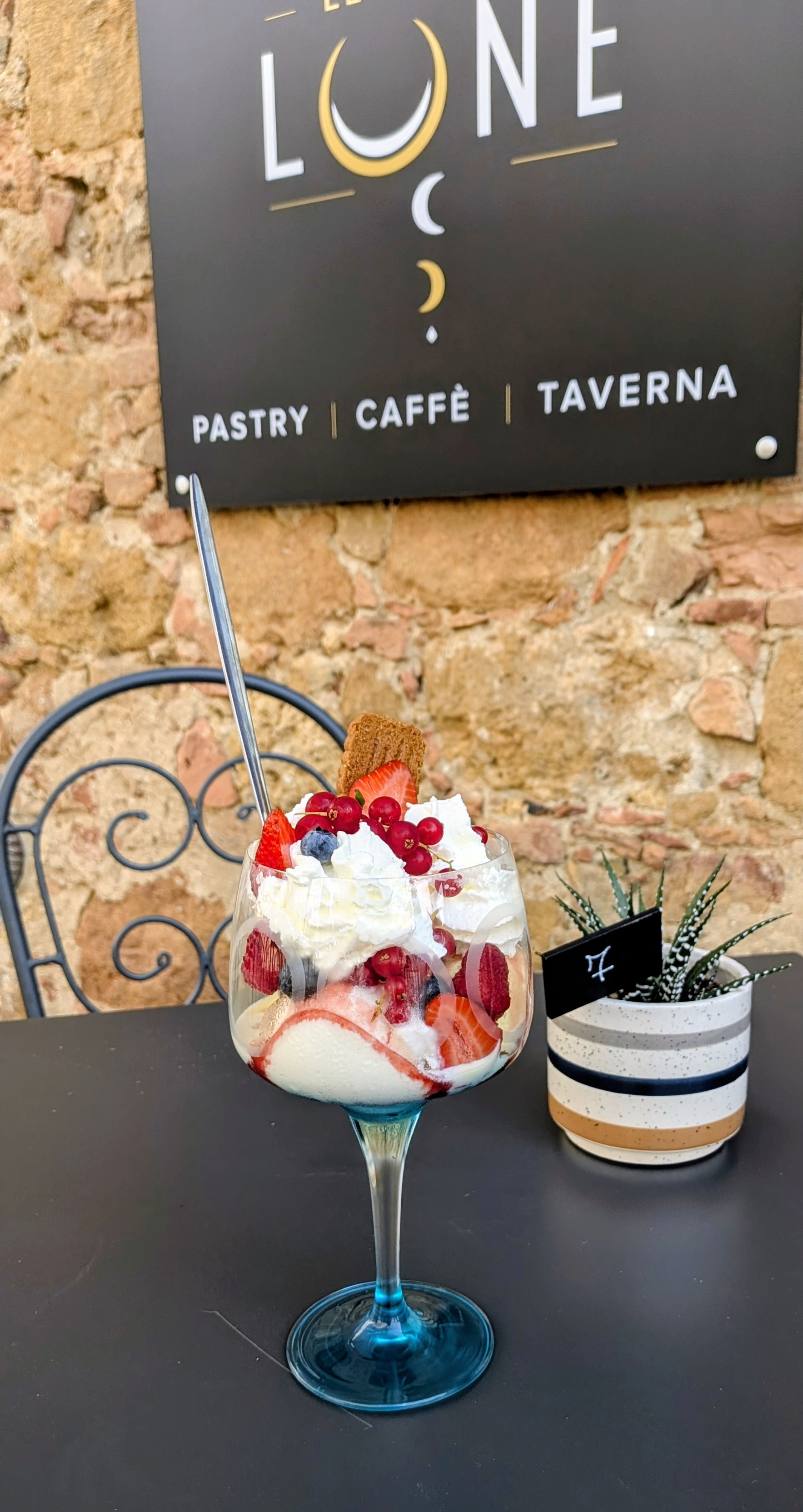 Coppa gelato con frutta e panna davanti all'insegna Le Cinque Lune